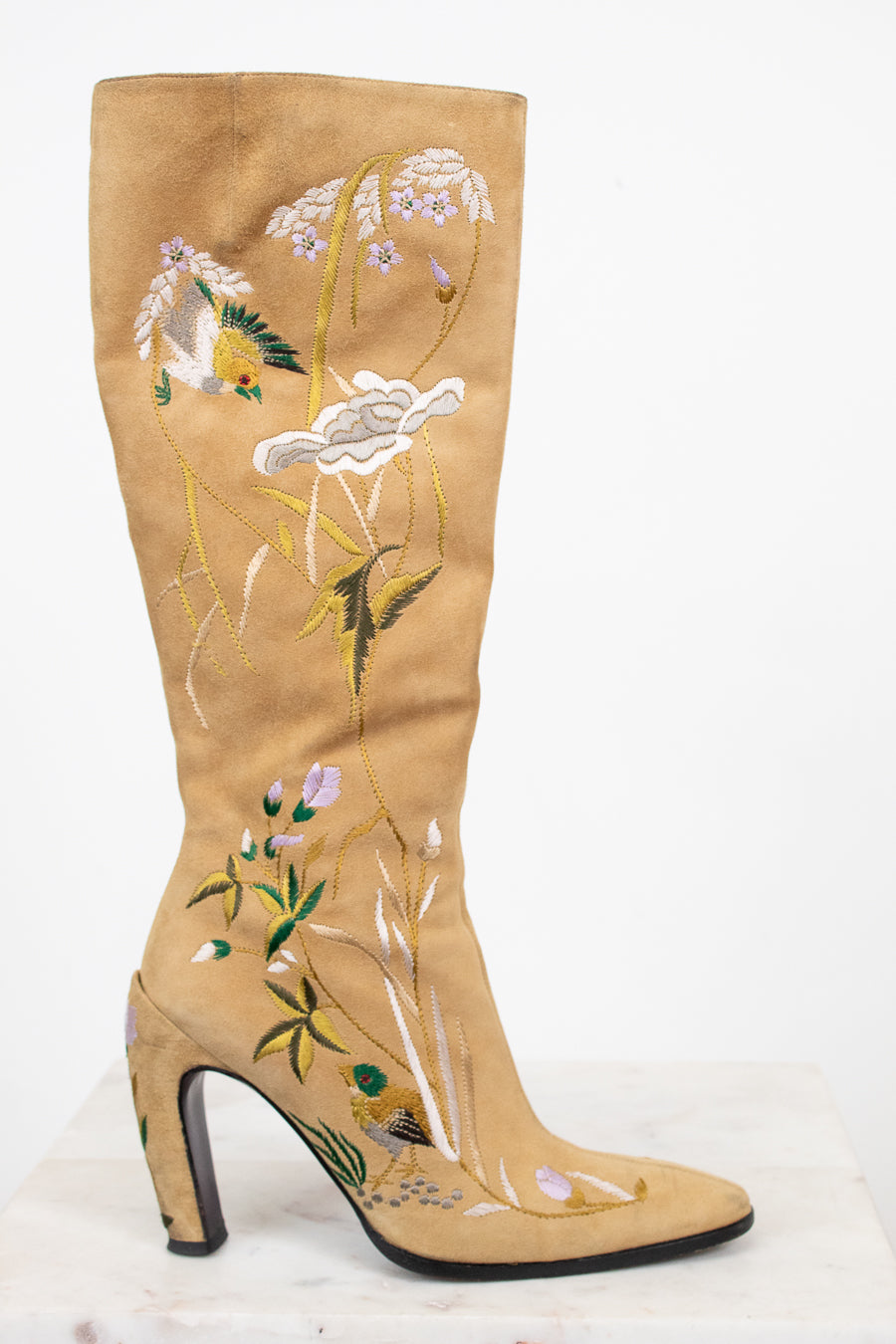 Beige knee-high boot with floral embroidery on a white background