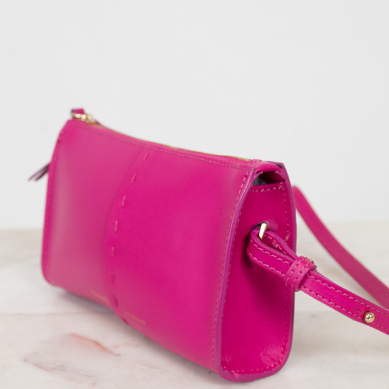 Pink crossbody bag on a light marble surface with a white background
