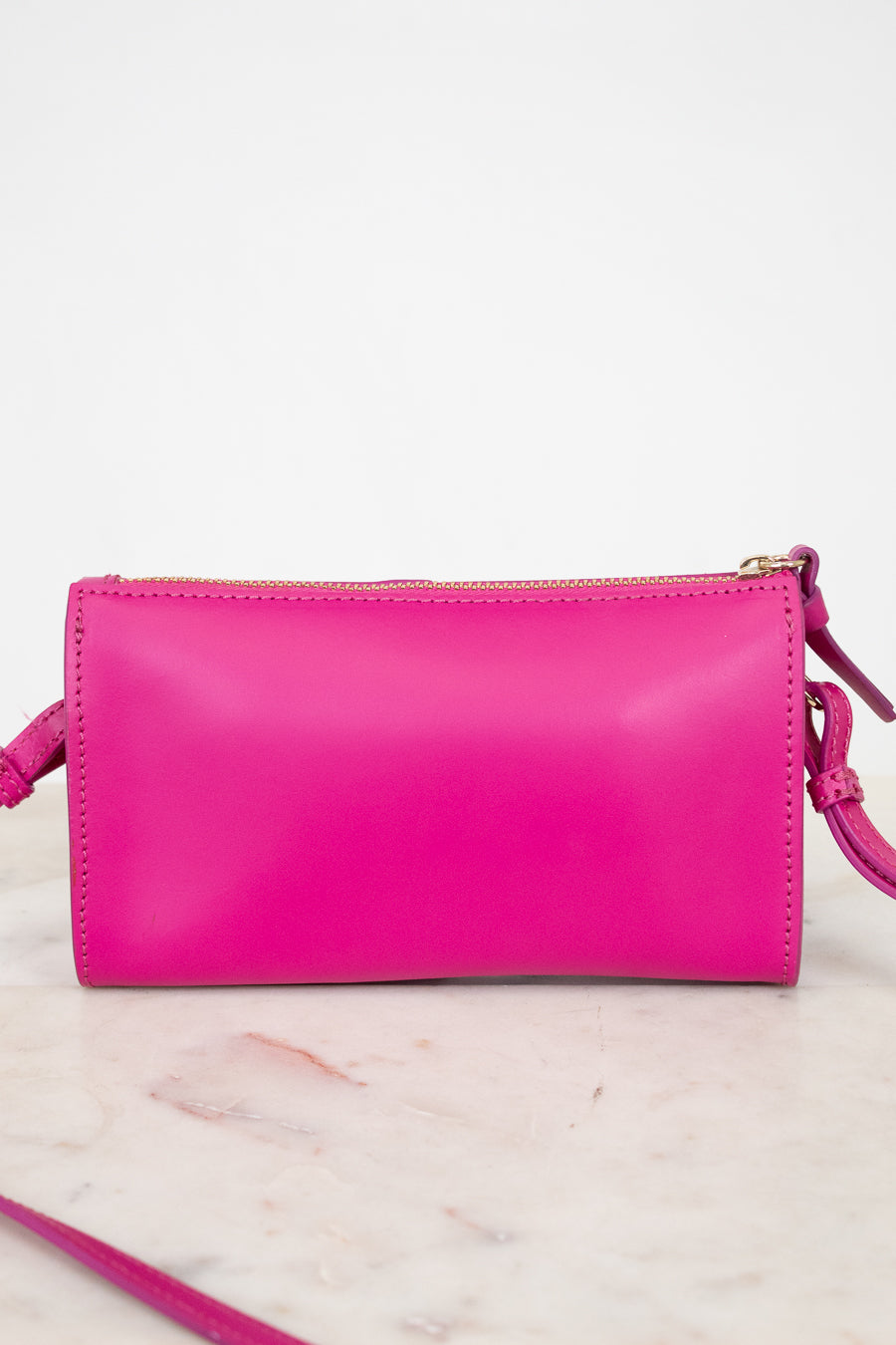 Pink crossbody handbag on a marble surface