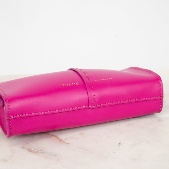 Pink crossbody bag with Frame/Les Second brand name on a light marble 
