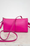 Pink crossbody bag with Frame/Les Second brand name on a light marble 