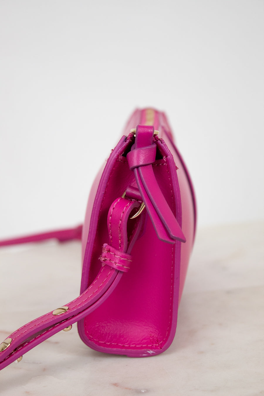 Pink handbag with gold accents on a light background