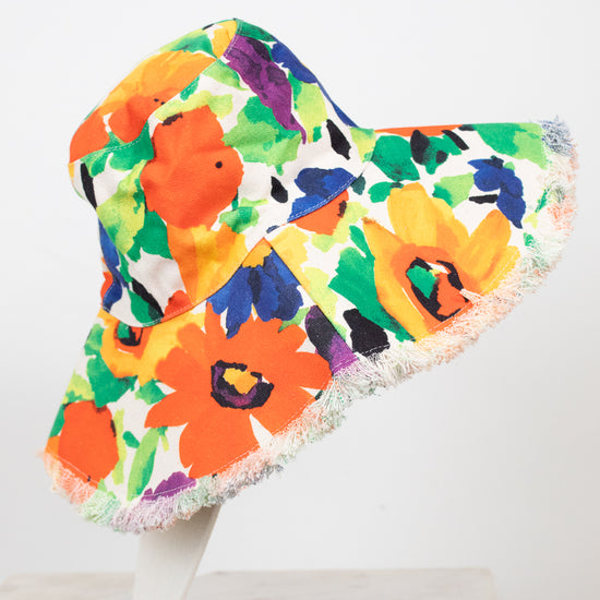Colorful floral bucket hat on a white stand against a white background