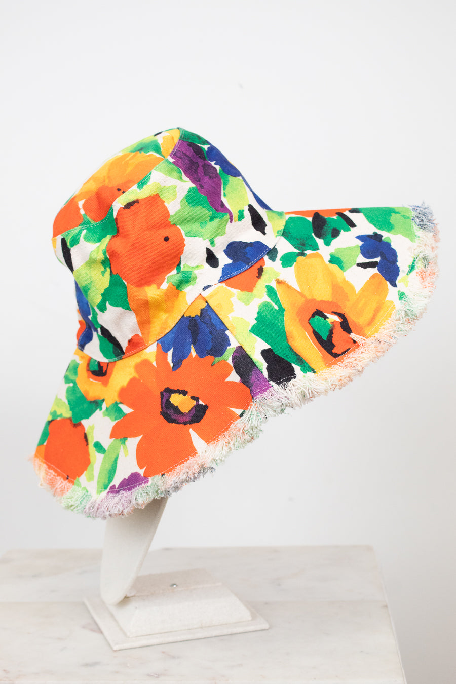 Colorful floral bucket hat on a white stand against a white background