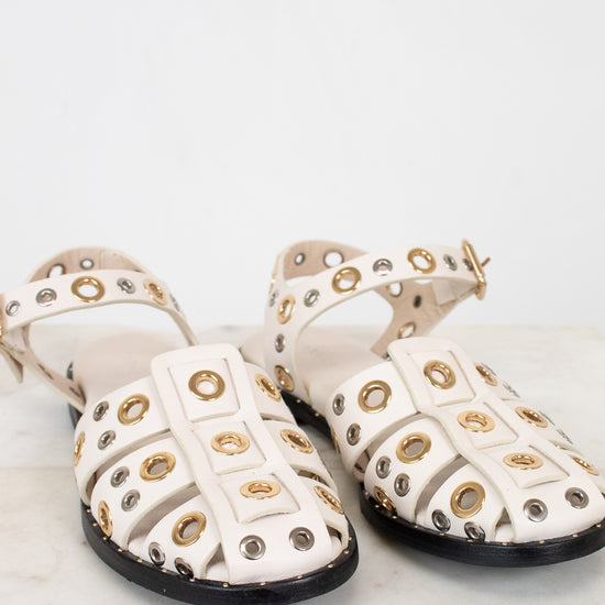 Pair of white sandals with gold and silver embellishments on a light background