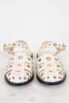 White sandals with gold  and silver embellishments on a light gray background