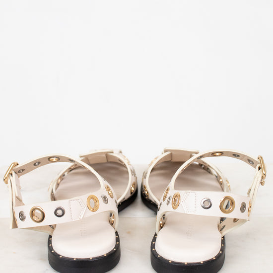 Pair of white sandals with gold and silver  accents on a marble surface