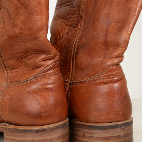 Close-up of brown leather boots with a worn texture on a light background