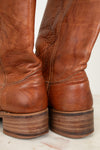 Close-up of brown leather boots with a worn texture on a light background