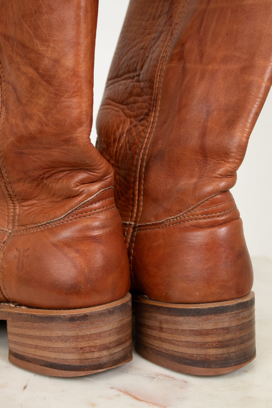 Close-up of brown leather boots with a worn texture on a light background
