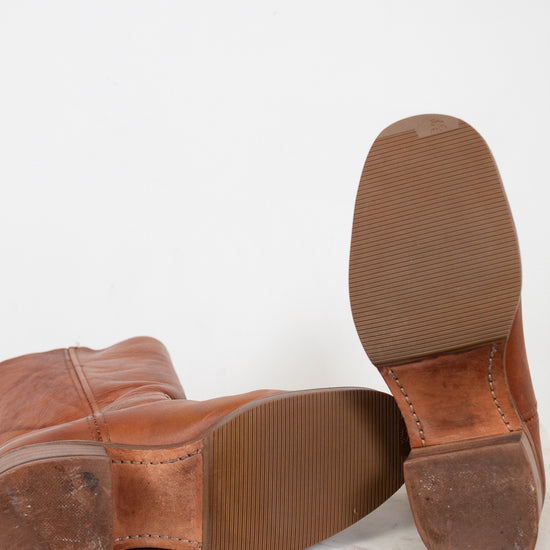 Brown leather shoes with worn soles on a white background