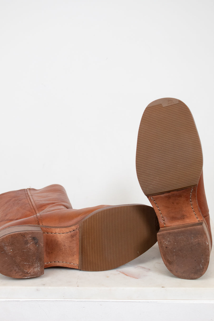 Brown leather shoes with worn soles on a white background