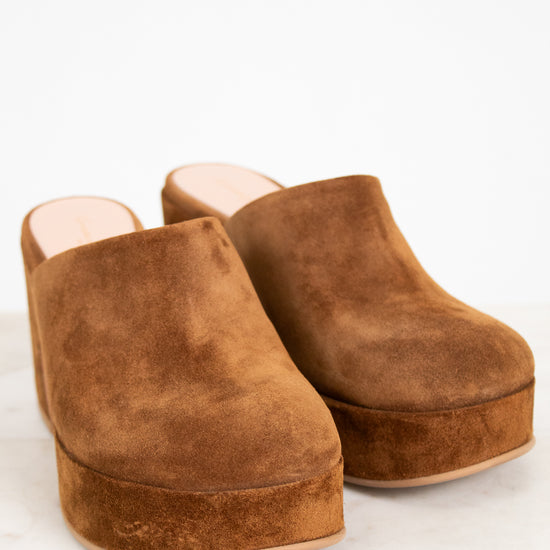 Pair of brown suede clogs on a white background
