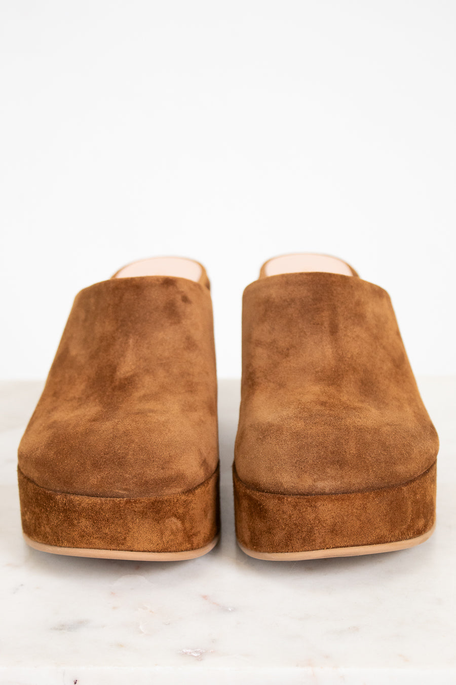 Pair of brown suede clogs on a white background