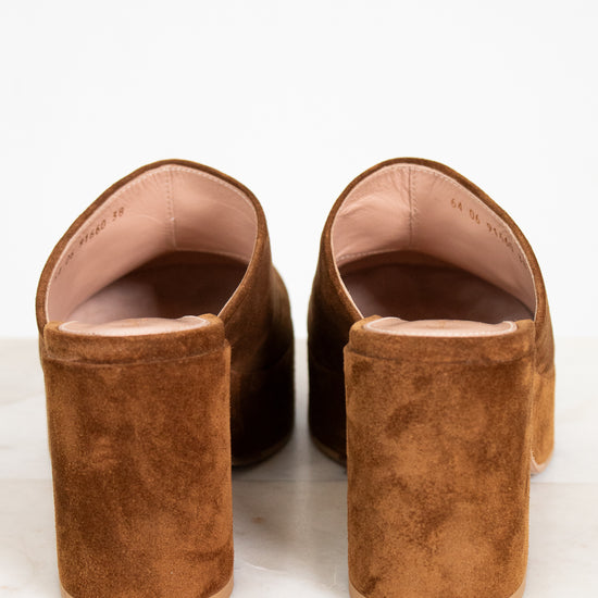 Pair of brown suede mules on a white background
