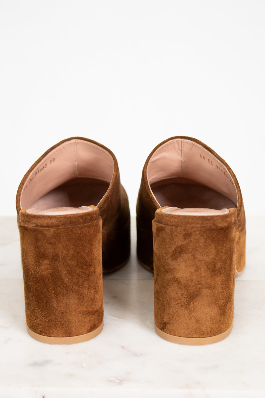 Pair of brown suede mules on a white background