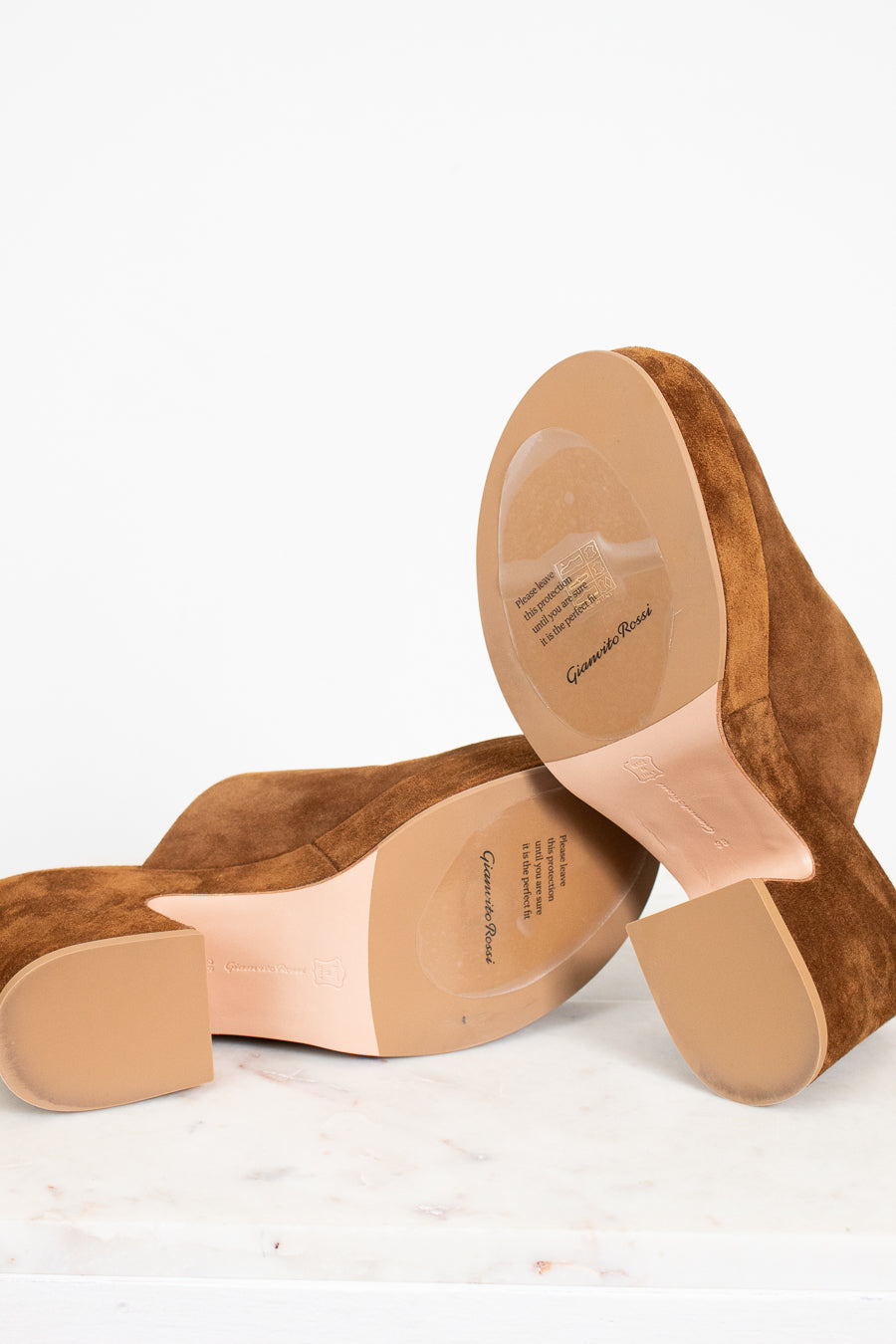 Brown suede shoes with beige soles on a white background