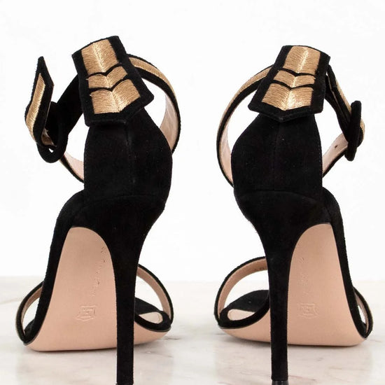 Black high-heeled shoes with gold accents on a white background