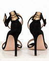 Black high-heeled shoes with gold accents on a white background