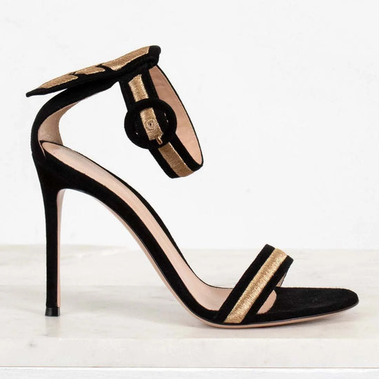 Black high-heeled sandal with gold accents on a white background