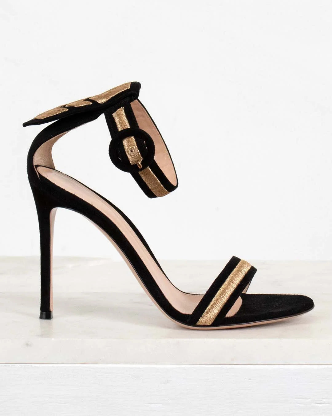 Black high-heeled sandal with gold accents on a white background