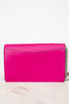 A bright hot pink leather clutch bag with a silver chain strap, resting on a light marble surface against a white background.