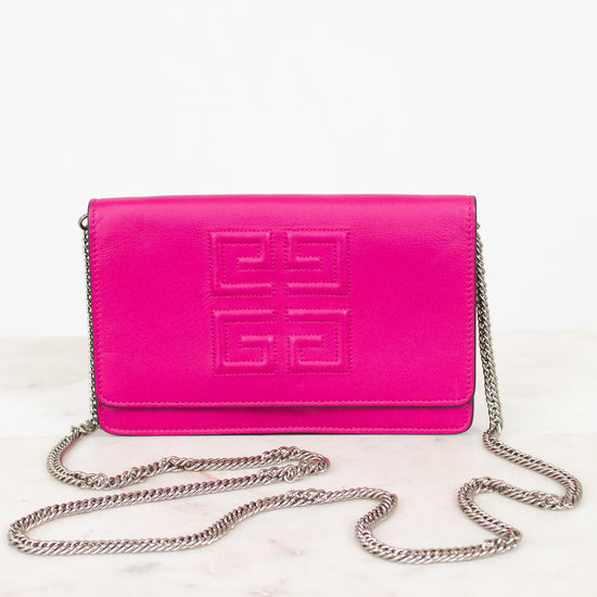 A bright pink Givenchy envelope clutch bag with embossed logo detailing on the front flap and a silver-tone chain strap, displayed on a light marble surface against a white background.