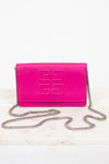 A bright pink Givenchy envelope clutch bag with embossed logo detailing on the front flap and a silver-tone chain strap, displayed on a light marble surface against a white background.