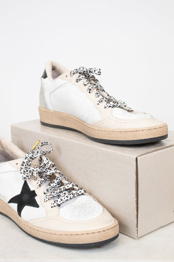 White sneakers with decorative laces on a white background
