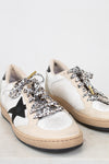 White sneakers with black star design and leopard print laces on a light background