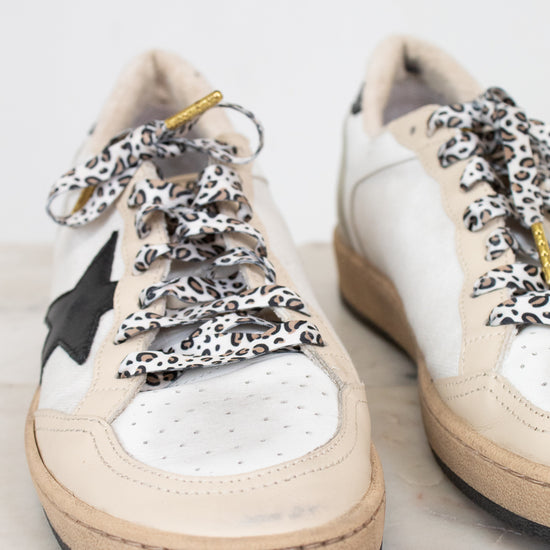 White sneakers with leopard print laces on a light background