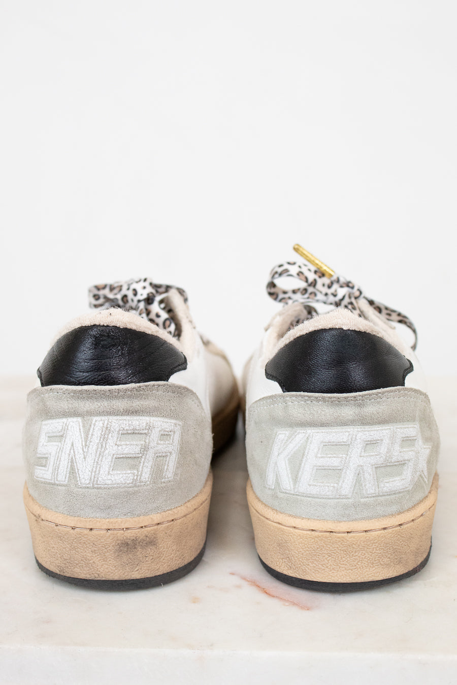 Pair of light gray sneakers with 'Sneakers branding on a white background