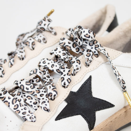 White sneakers with leopard print laces and a black star on a light background