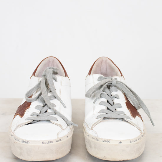White sneakers with brown accents on a light gray background