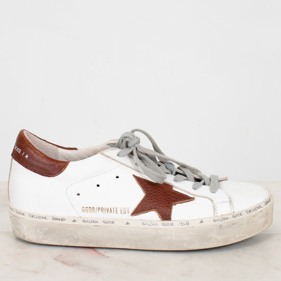 White sneaker with a brown star on a light gray background