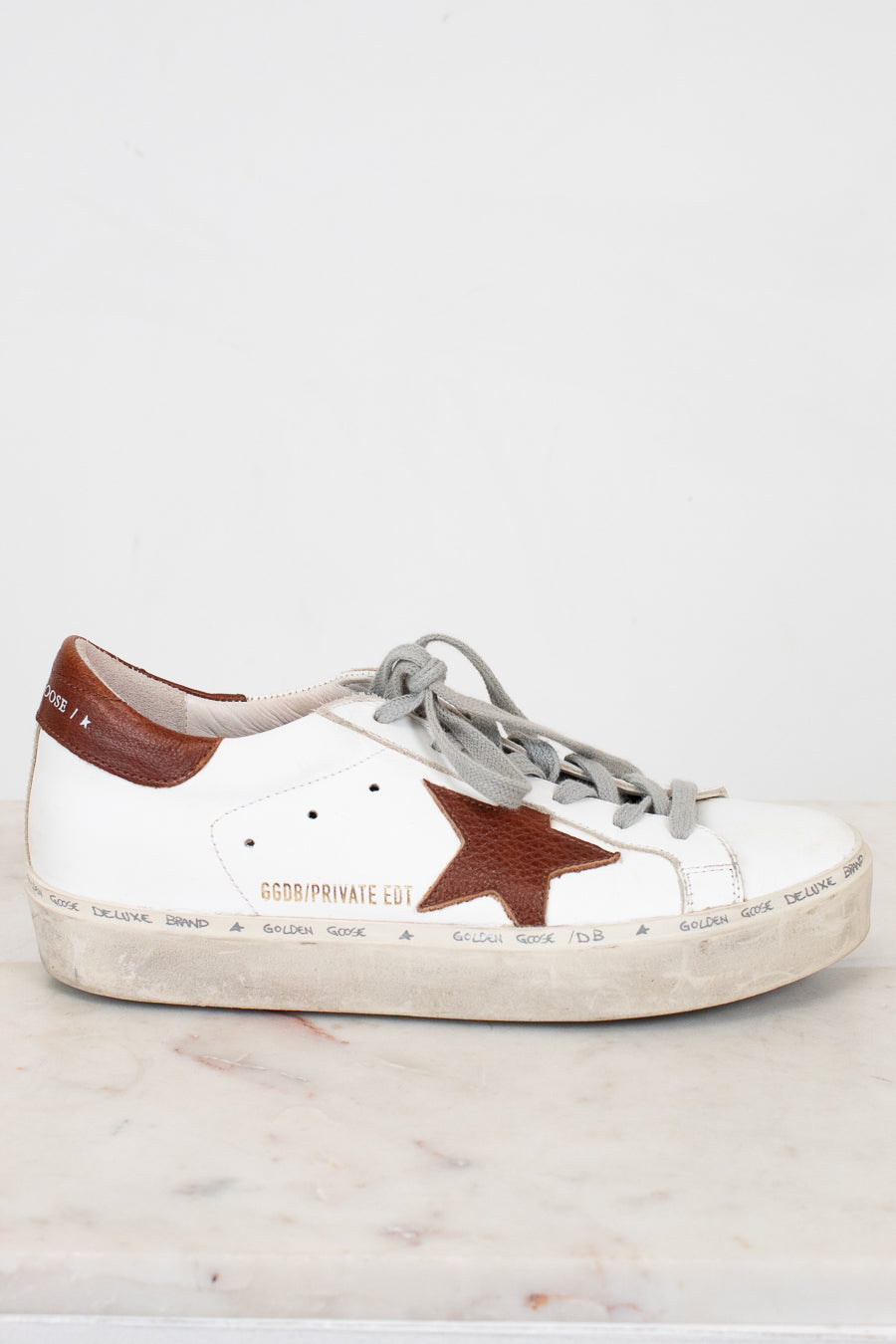White sneaker with a brown star on a light gray background