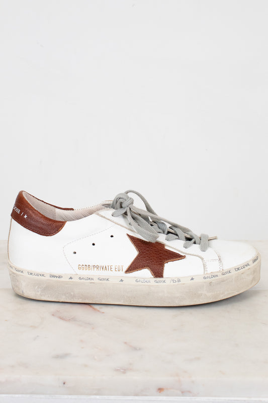 White sneaker with a brown star on a light gray background