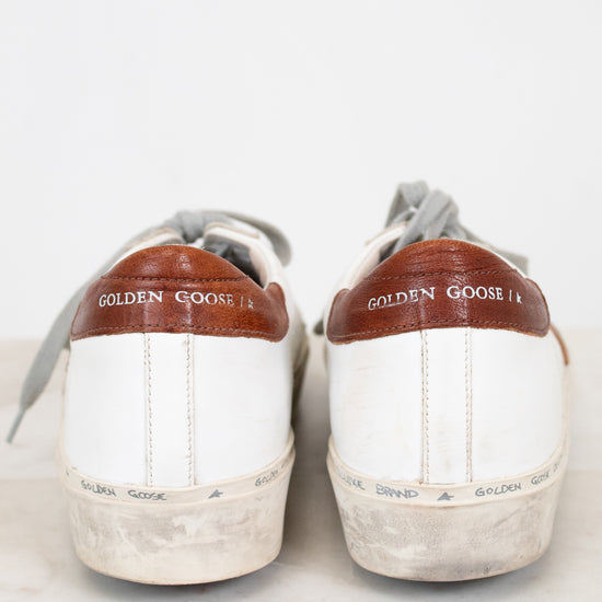 Pair of white sneakers with brown accents and 'Golden Goose' branding on a light background