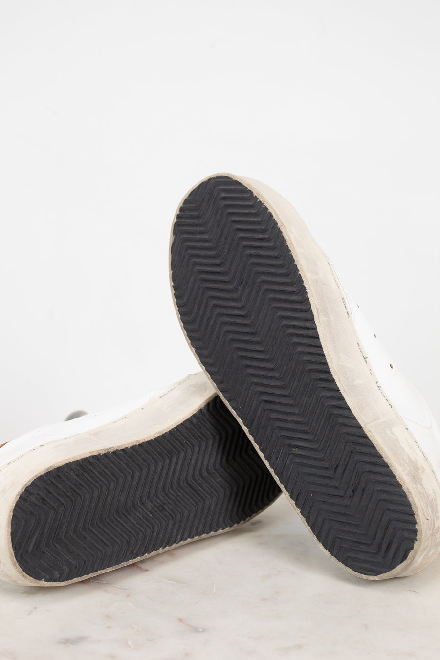 Close-up of a pair of sneakers with black soles on a light gray background