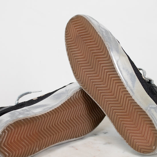 Close-up of black sneakers with brown soles on a light gray background