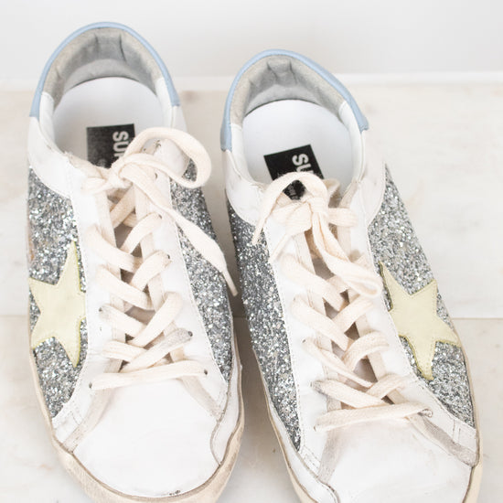 Pair of glittery sneakers with white laces on a light background