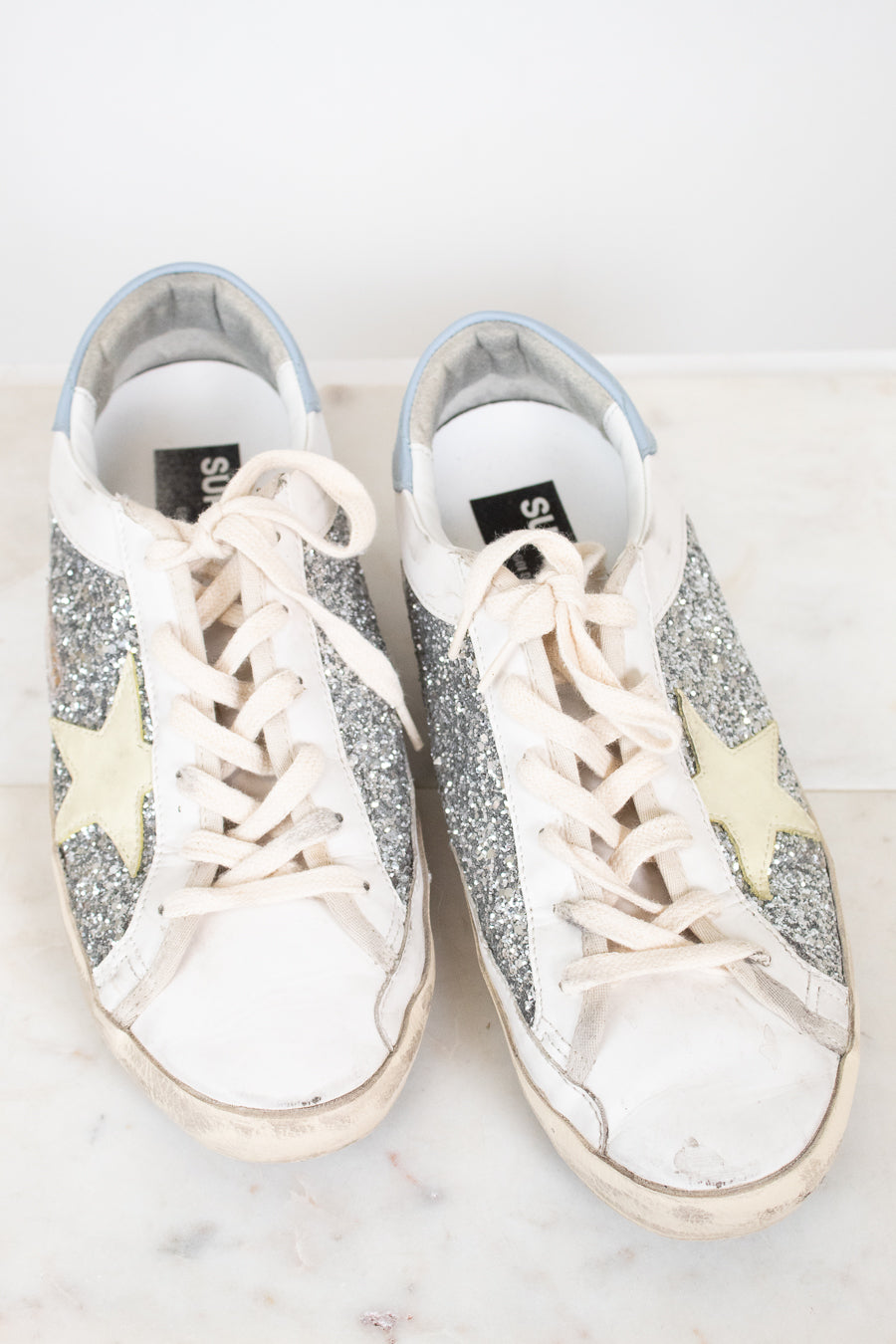 Pair of glittery sneakers with white laces on a light background
