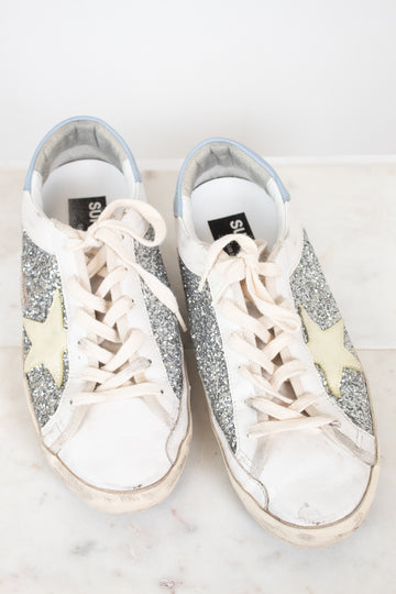 Pair of glittery sneakers with white laces on a light background