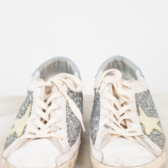 Pair of white sneakers with glittery accents on a light background