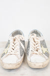 Pair of white sneakers with glittery accents on a light background