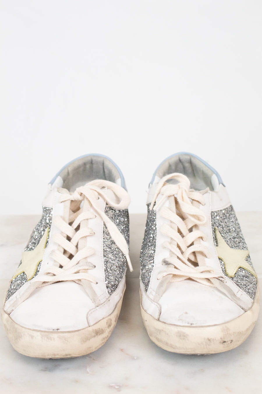Pair of white sneakers with glittery accents on a light background