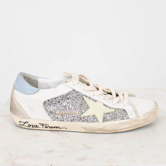 White sneaker with glittery details and star design and brand name on a white background