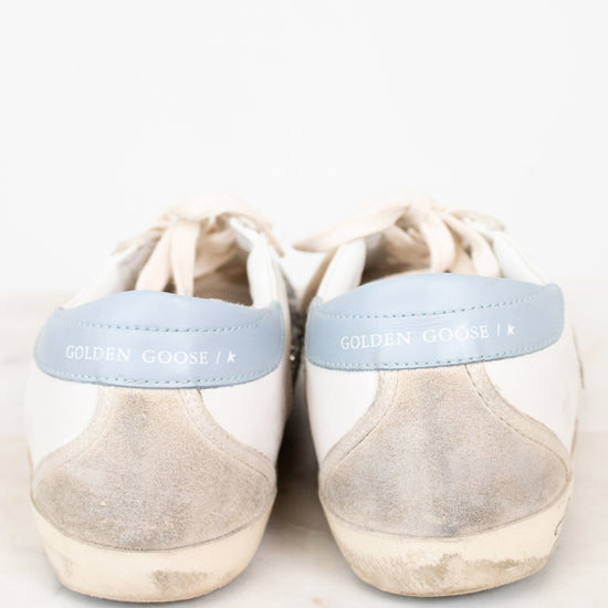 Pair of beige sneakers with light blue accents on a white background