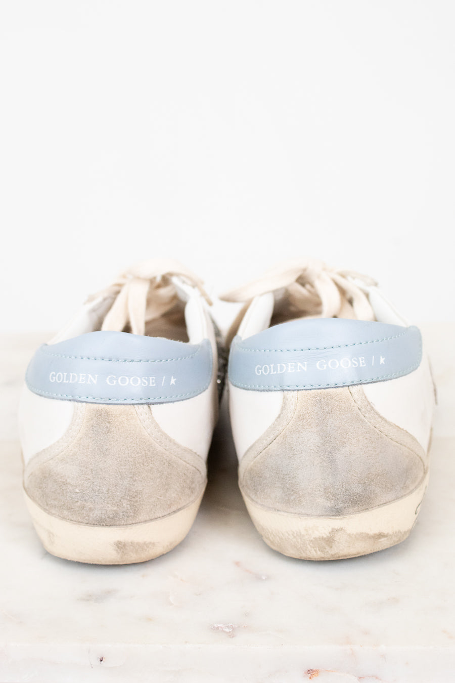Pair of beige sneakers with light blue accents on a white background