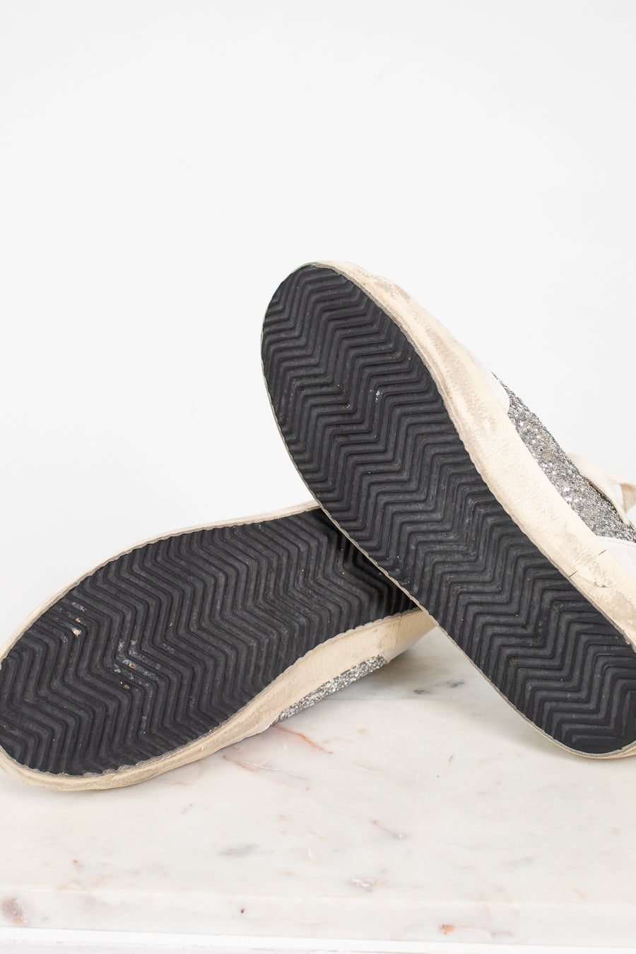 Close-up of a pair of shoes with textured soles on a light background